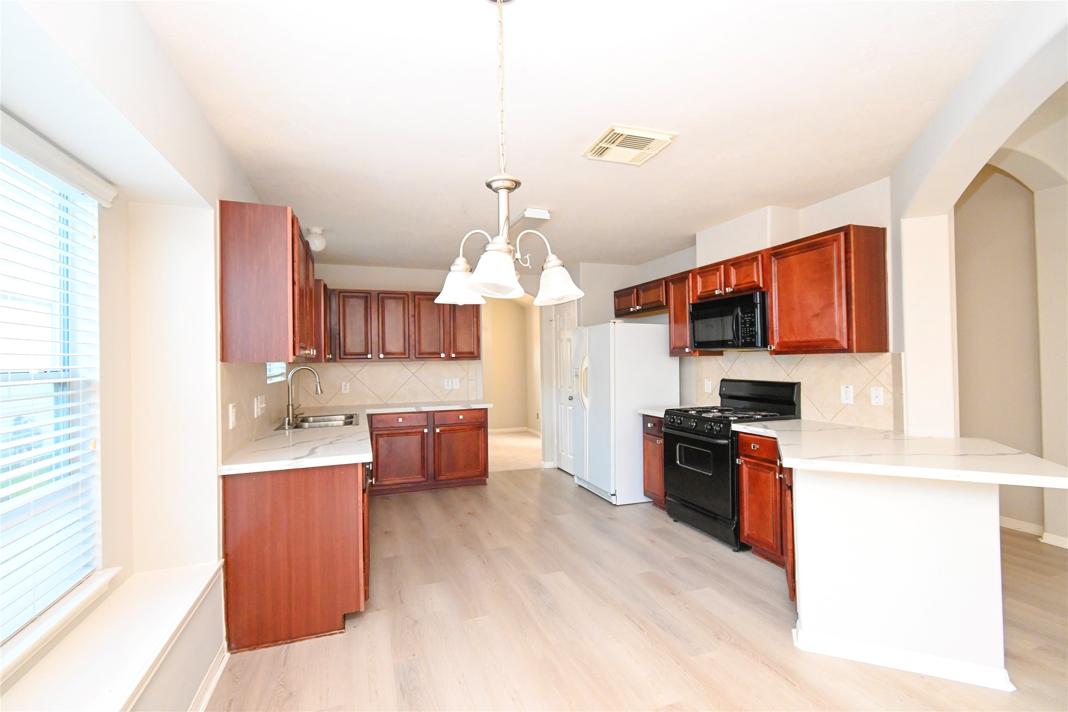 3111 Myrtle Ranch Drive Katy, TX 77494 - Photo 16 of 27 a open kitchen with stainless steel appliances kitchen island granite countertop a stove top oven a sink dishwasher and a refrigerator with wooden floor