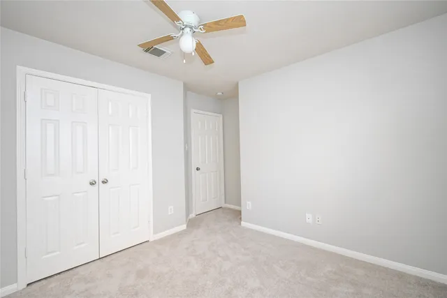 an empty room with a window and a fan