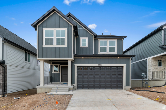 View of front facade with board and batten siding, an attached garage, and driveway