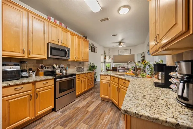 a kitchen with stainless steel appliances granite countertop wooden cabinets a stove top oven a sink and dishwasher