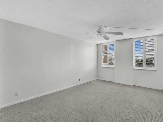 an empty room with a ceiling fan and window