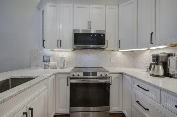 a kitchen with granite countertop white cabinets and stainless steel appliances