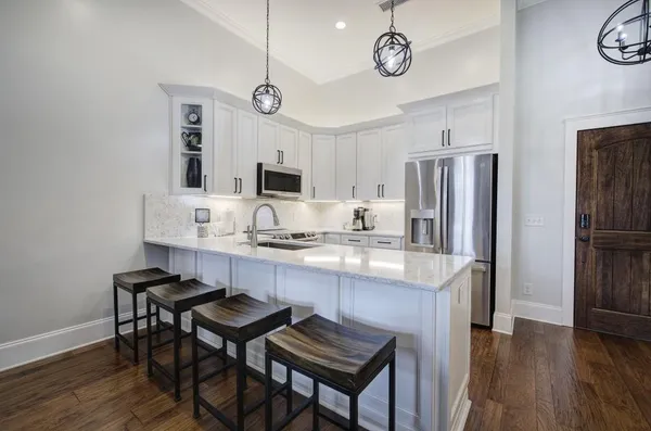 a kitchen with kitchen island granite countertop a table chairs a sink refrigerator and cabinets