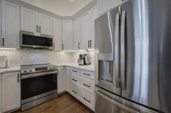 a kitchen with stainless steel appliances white cabinets and a stove top oven