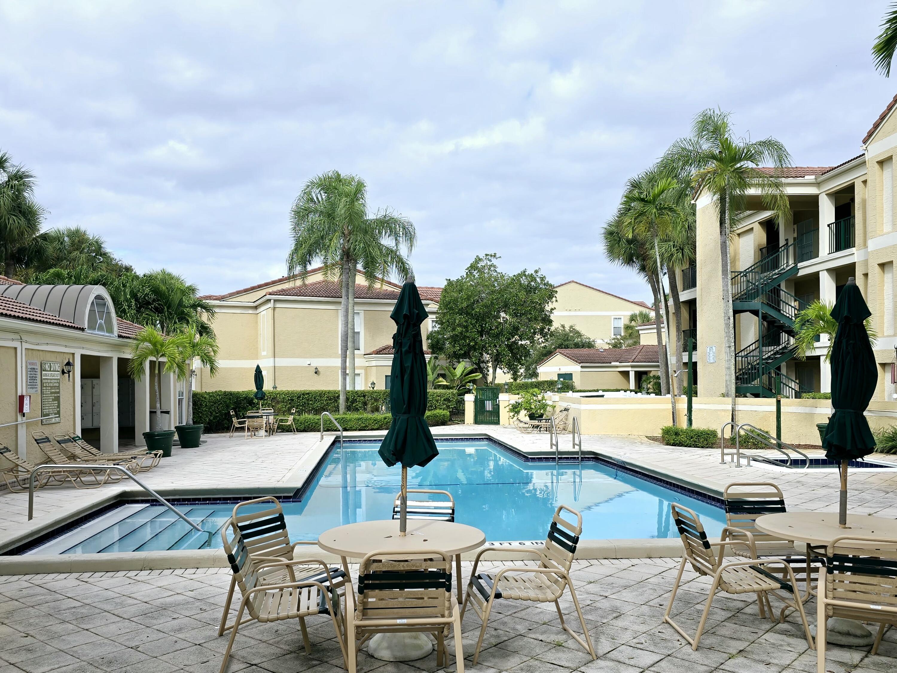 977 Riverside Drive, Unit 220 Coral Springs, FL 33071 - Photo 21 of 23 a view of a patio with couches table and chairs under an umbrella