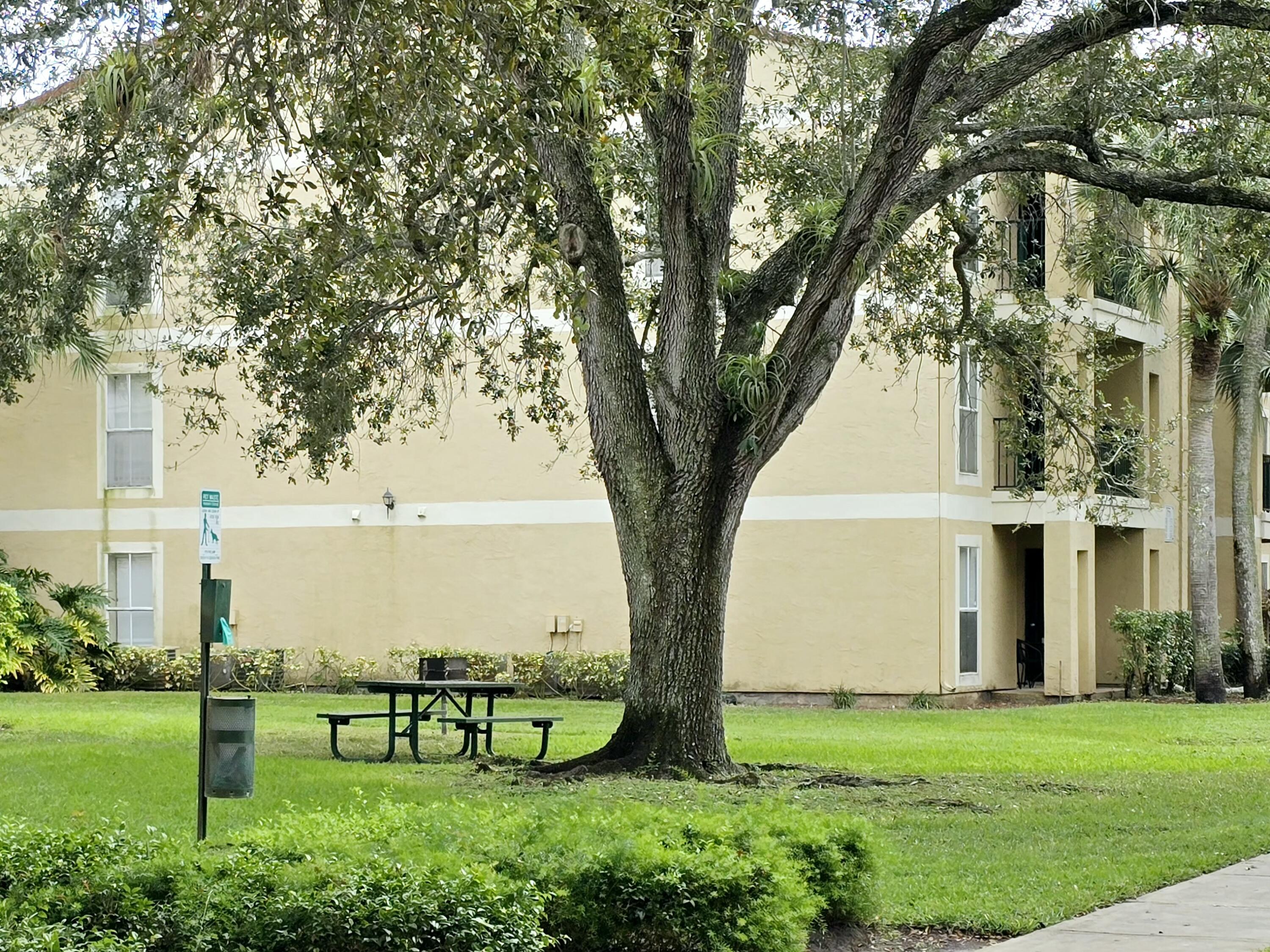 977 Riverside Drive, Unit 220 Coral Springs, FL 33071 - Photo 22 of 23 a view of a white house with a big yard and large trees
