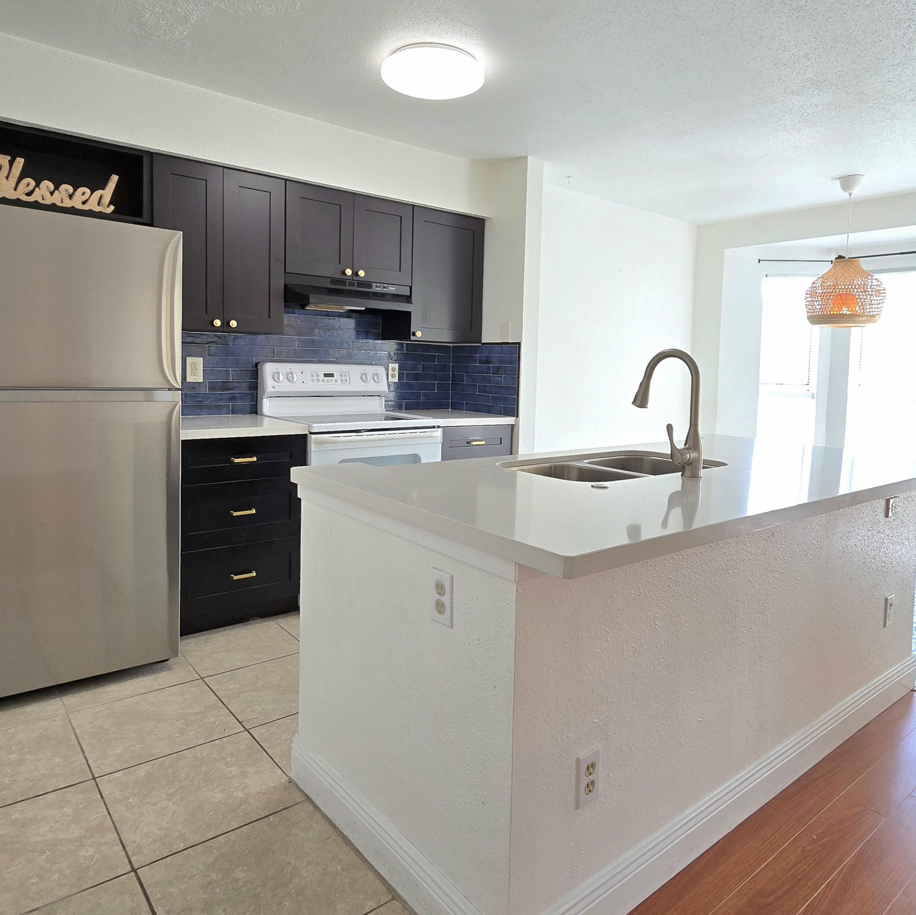 977 Riverside Drive, Unit 220 Coral Springs, FL 33071 - Photo 7 of 23 a kitchen with a refrigerator sink and cabinets
