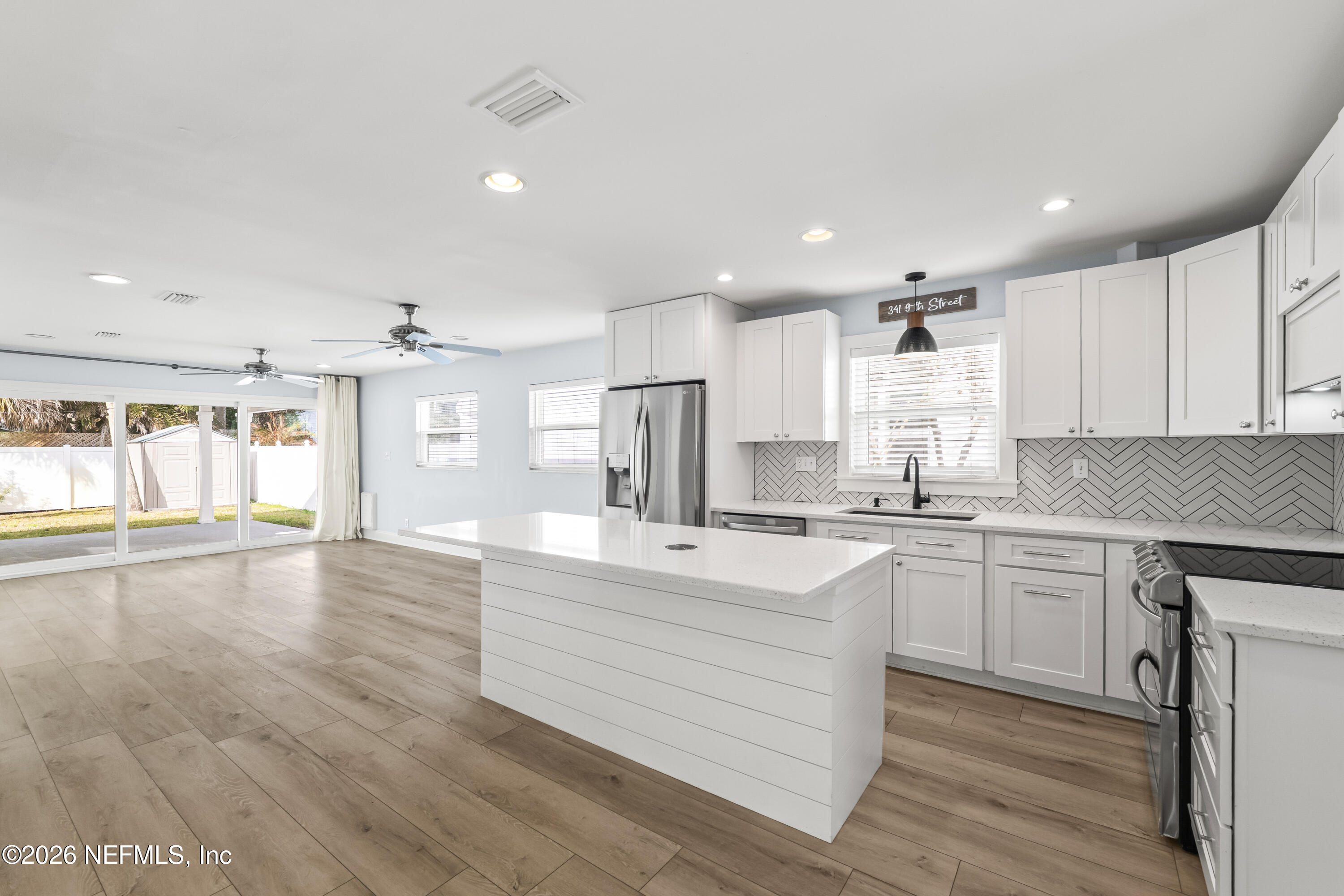 341 9th Street Atlantic Beach, FL 32233 - Photo 6 of 35 a large white kitchen with wooden floors and white cabinets