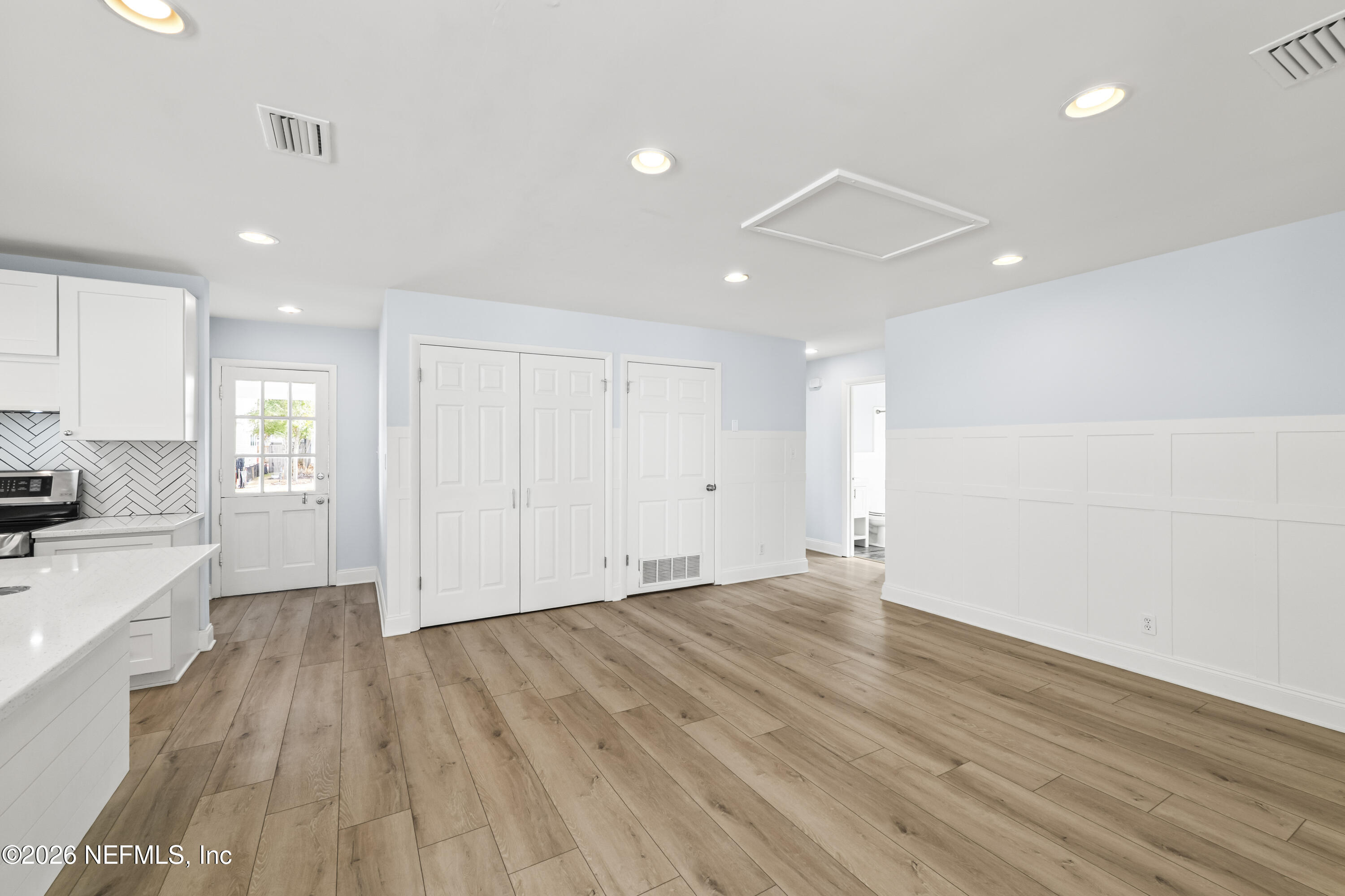 341 9th Street Atlantic Beach, FL 32233 - Photo 7 of 35 a view of an empty room with wooden floor and a kitchen