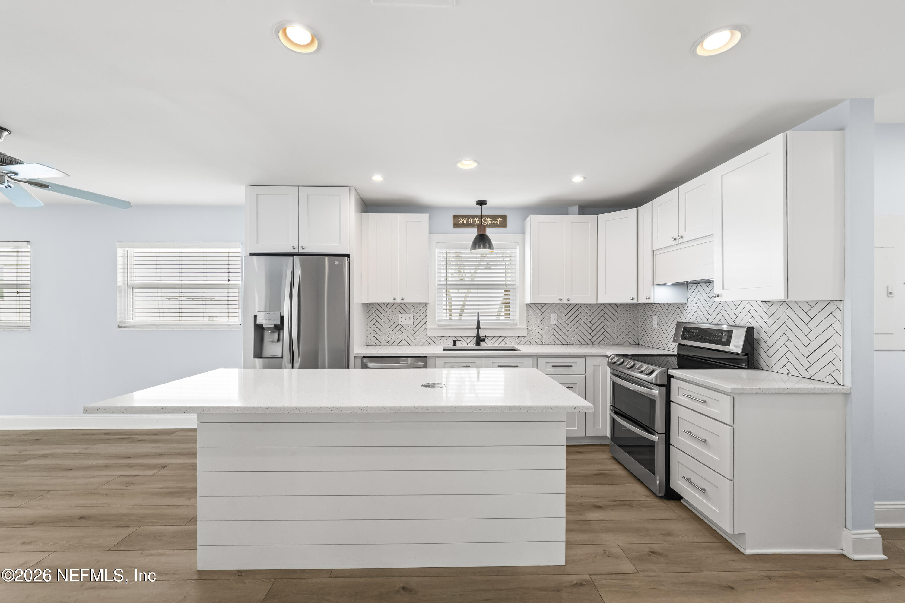 341 9th Street Atlantic Beach, FL 32233 - Photo 9 of 35 a large kitchen with stainless steel appliances granite countertop a stove a sink a refrigerator and white cabinets with wooden floor