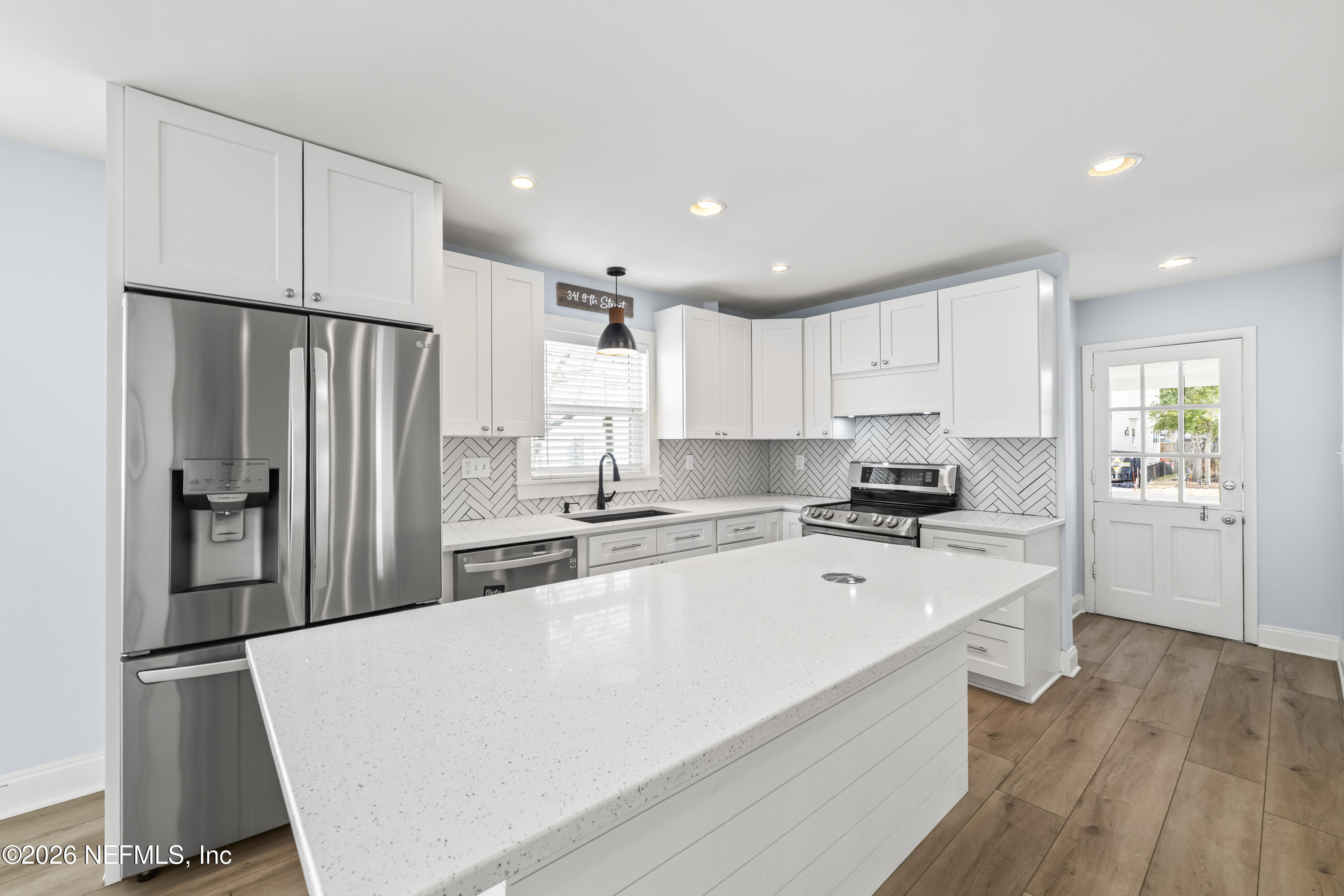 341 9th Street Atlantic Beach, FL 32233 - Photo 10 of 35 a large kitchen with a refrigerator a sink dishwasher a stove and white cabinets with wooden floor