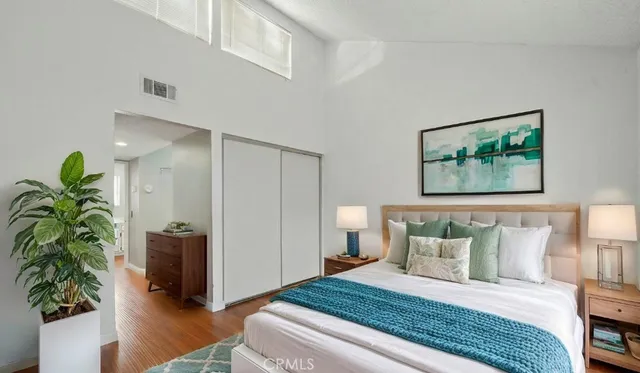 a bedroom with a bed a dresser and a potted plant