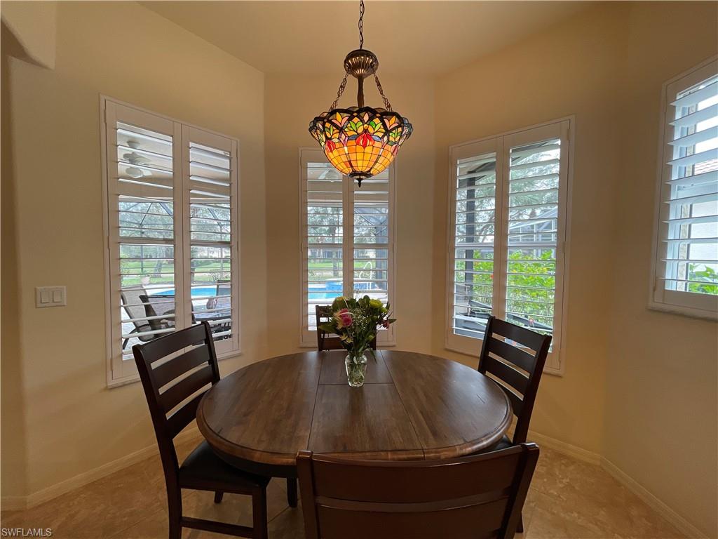 6478 Waverly Green Way Naples, FL 34110 - Photo 14 of 28 a dining room with furniture a chandelier and wooden floor