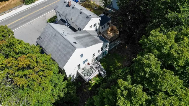 a view of a white house with a big yard and large trees