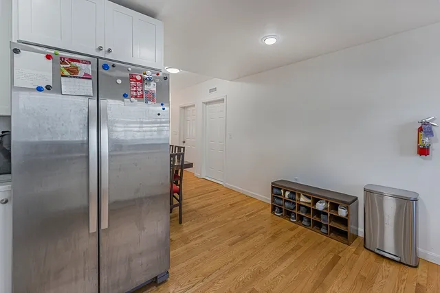a kitchen with refrigerator and wooden floor