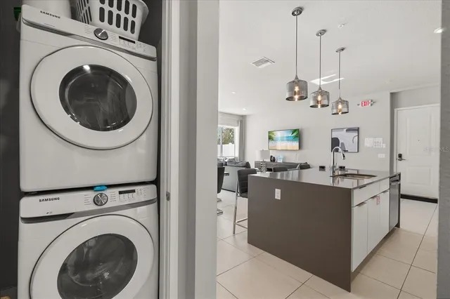 a living room with kitchen island a sink a washer and dryer