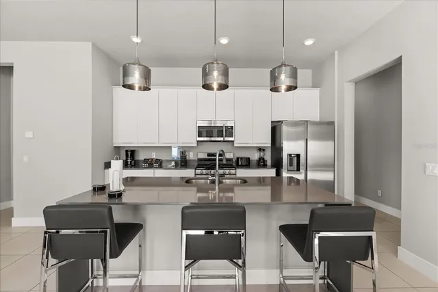 a kitchen with stainless steel appliances granite countertop a sink a stove a refrigerator and chairs