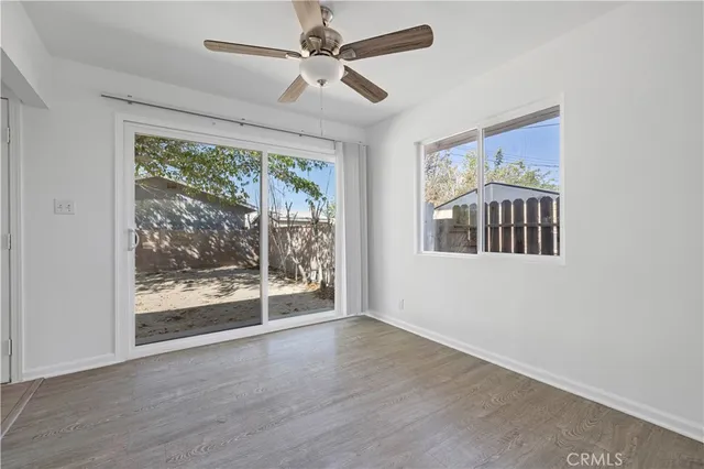 an empty room with wooden floor fan and windows