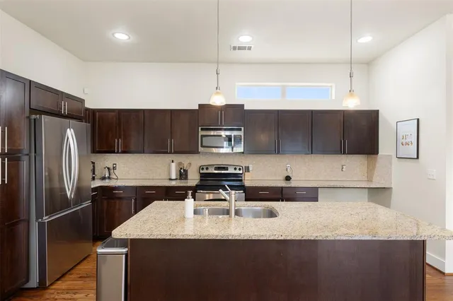 a kitchen with stainless steel appliances granite countertop a sink a stove and a refrigerator