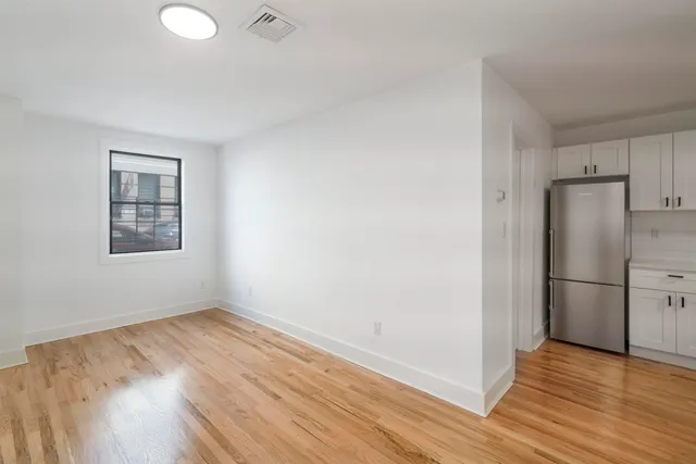a view of a kitchen with wooden floor and a refrigerator