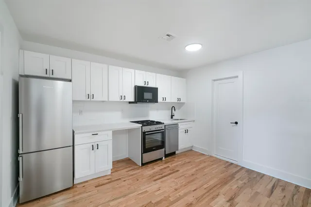 a kitchen with a refrigerator stove and white cabinets