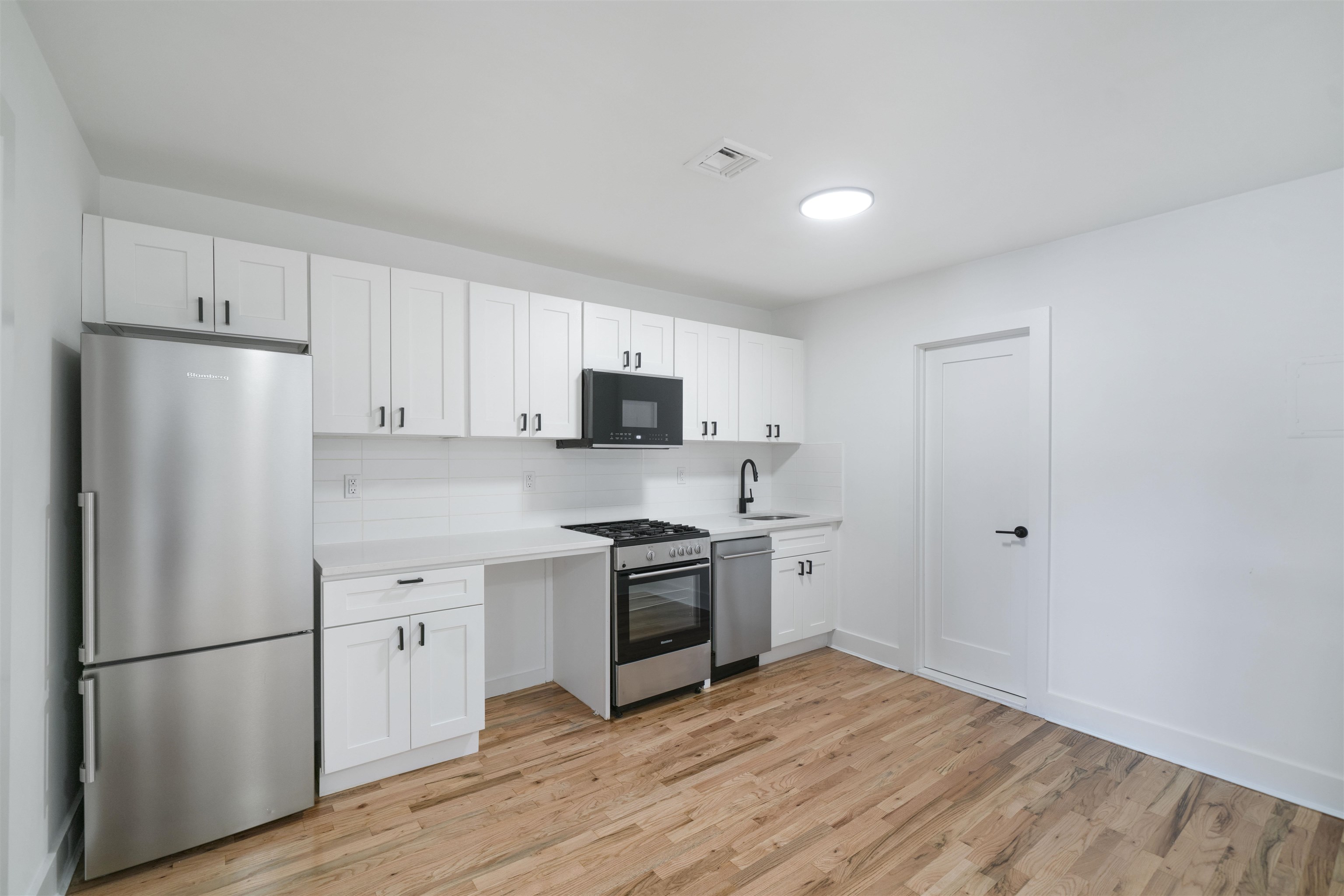 163 3rd Street, Unit 1A Hoboken, NJ 07030 - Photo 6 of 12 a kitchen with a refrigerator stove and white cabinets
