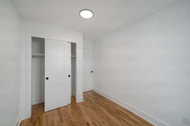 a view of hallway with closet and wooden floor