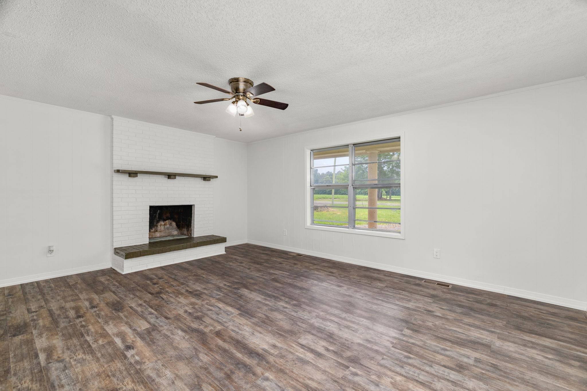 217 Red Bay Road Golden, MS 38847 - Photo 4 of 33 Spacious living area featuring a white brick fireplace with a dark wood mantel and hearth