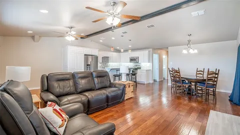 a living room with furniture kitchen view and a chandelier
