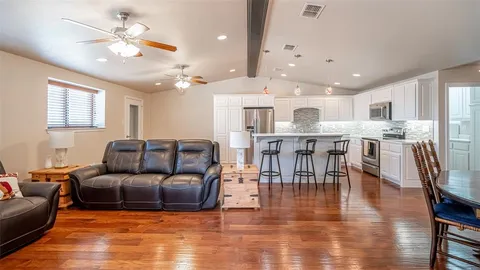 a living room with furniture kitchen view and a wooden floor