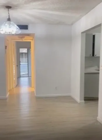 a view of a hallway with wooden floor and a kitchen