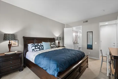 a bedroom with a bed a chair and a flat tv screen on the dresser