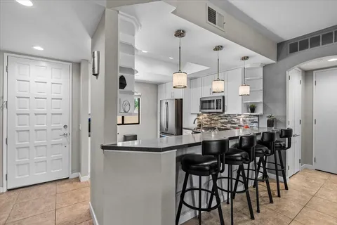 a kitchen with stainless steel appliances kitchen island granite countertop a table chairs sink and cabinets