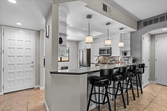 a kitchen with stainless steel appliances kitchen island granite countertop a table chairs sink and cabinets