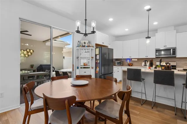 a kitchen with stainless steel appliances a dining table chairs refrigerator and cabinets