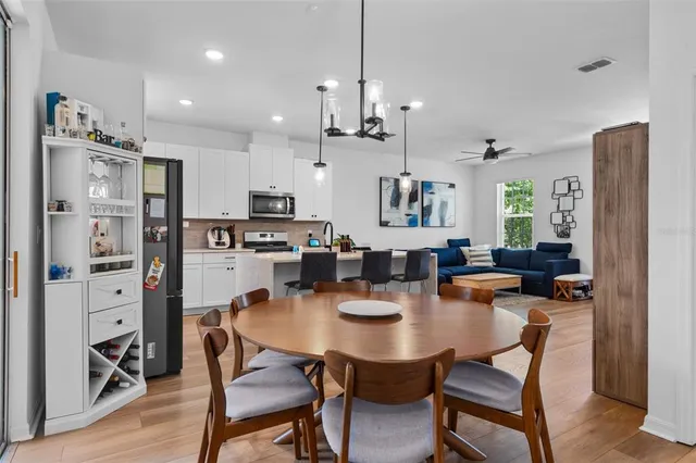a dining room with stainless steel appliances kitchen island granite countertop a dining table chairs and a refrigerator