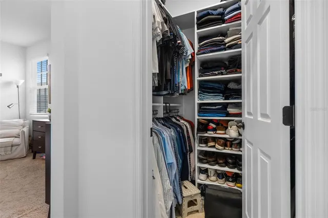 a view of walk in closet with clothes and shoes