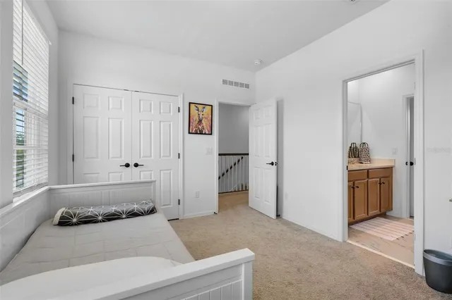 a spacious bedroom with a bed and a view of kitchen
