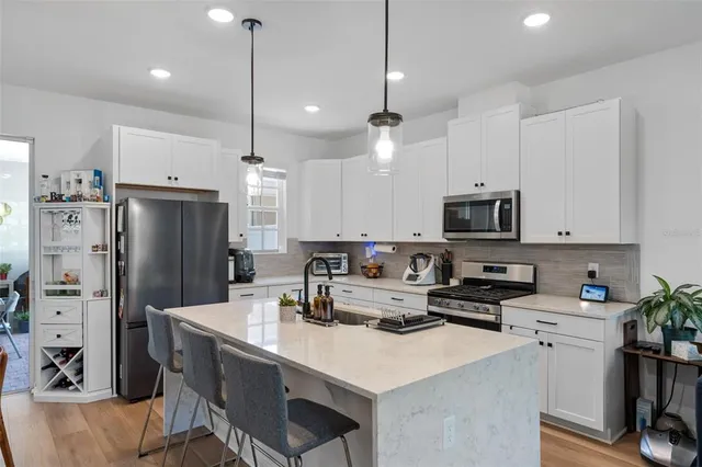 a kitchen with stainless steel appliances granite countertop a refrigerator a stove a sink dishwasher and a refrigerator with wooden floor