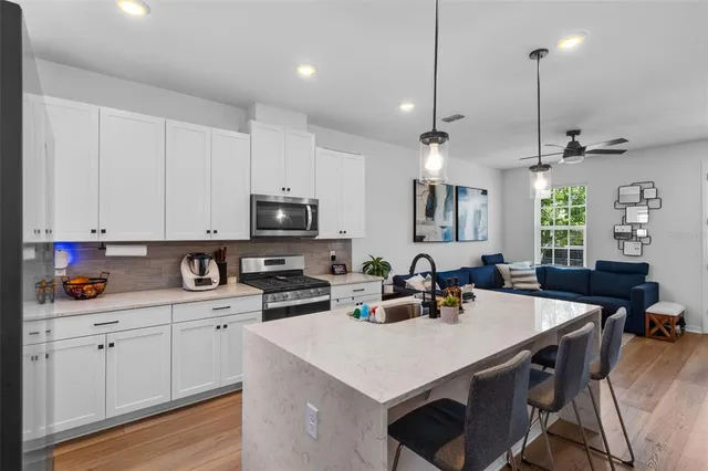 a kitchen with stainless steel appliances a table chairs sink and cabinets