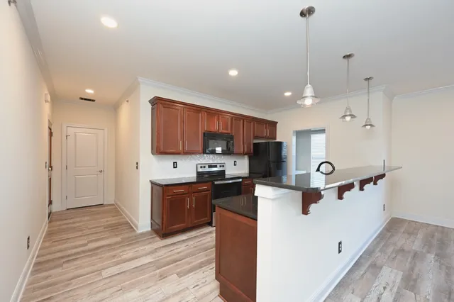 a kitchen with stainless steel appliances granite countertop a sink a stove and a wooden floors