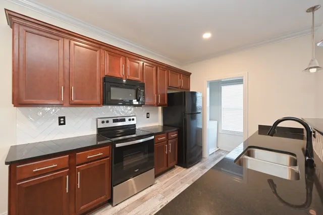 a view of an empty room with wooden floor and fan