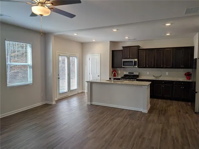 a kitchen with granite countertop wooden floors stainless steel appliances and window