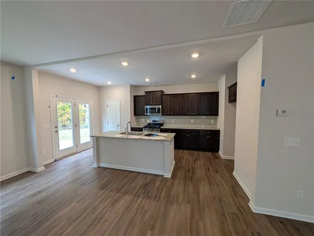 a view of kitchen with kitchen island wooden floor center island and stainless steel appliances