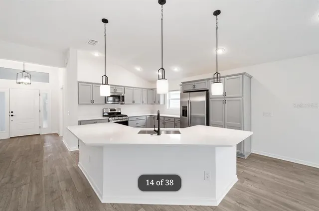 a view of kitchen with kitchen island a sink a center island and wooden floor