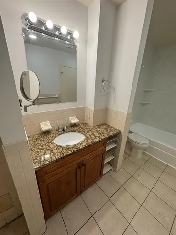 a bathroom with a granite countertop sink a toilet and a mirror