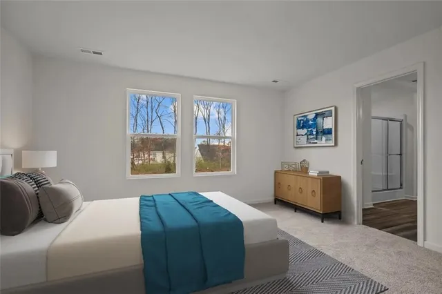 a bedroom with a bed couch and two windows