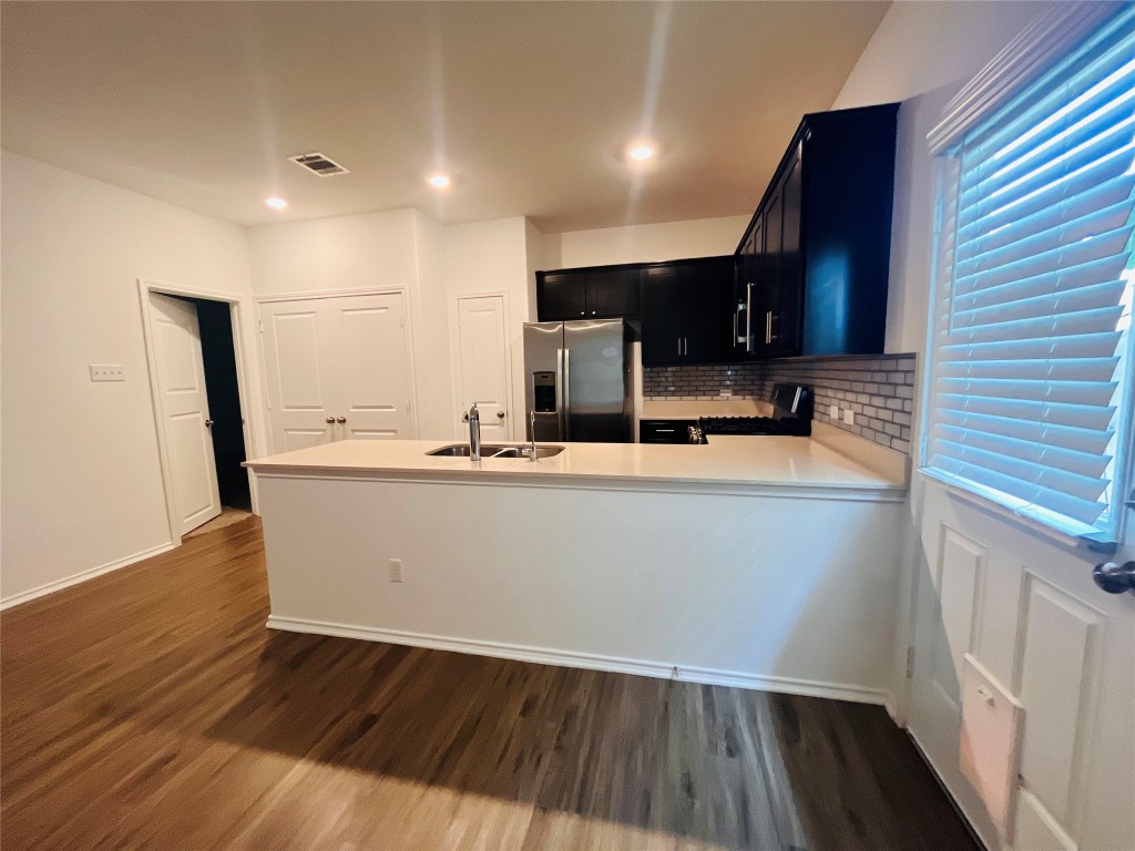 325 Geode Glen Maxwell, TX 78656 - Photo 9 of 28 Kitchen featuring stainless steel refrigerator with ice dispenser, dark cabinets, dark wood-style floors, light countertops, and recessed lighting