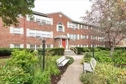 a front view of a multi story residential apartment building with yard and green space