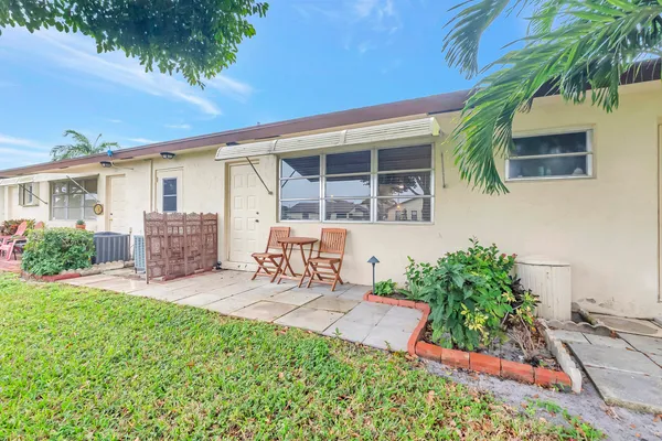 a view of a backyard with table and chairs potted plants and a house